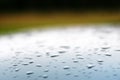 Background with blurred drops on the roof of a silver blue car and a green backdrop. Royalty Free Stock Photo