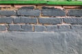 Background of Brick wall painted in grey with pink gaps , green stripe on top Royalty Free Stock Photo