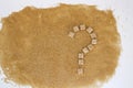 Background of brown sugar cubes shaped as a question mark. Top view. Diet unhealty sweet addiction concept
