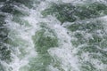 Background of churning bubbling green water behind a boat on the lake