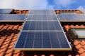 Background and close-up of a solar panel on a roof of a family home with red roof tiles, against a blue sky with clouds and Royalty Free Stock Photo