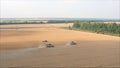 New harvesters on the field collect wheat. Panoramic view on the field of collected wheat. On the background the combine harvester