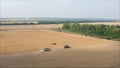 New harvesters on the field collect wheat. Panoramic view on the field of collected wheat. On the background the combine harvester