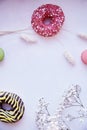 Background with copy space on purple vintage surface. Bright colorful macaroons, donuts, gypsophila. Happy holidays or
