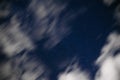 Background of dark-blue night sky with countless twinkle stars and moving white clouds upon on it Royalty Free Stock Photo