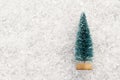 Souvenir Christmas tree on white snow. Background for the design of cards on the theme of the winter holidays. Copy space