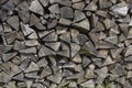 Background of dry chopped firewood laid in a woodpile. Grass at the pile of firewood.Grass at the pile of firewood. Close-up Royalty Free Stock Photo