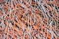 Background of an electric fence with its many plastic threads lying in a heap. The synthetic threads are orange and white. The