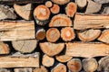 Background of ends of logs and dry firewoods. Close-up of outdoor stack of wood on a sunny day. Folded and packaged firewood.