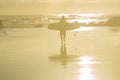 Background faded image of surfer walking into sunrise and water carrying surfboard