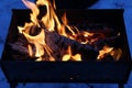 Background of fire and black wood. Dark grey, black white coals on bright fire inside metal brazier. Wood burning in the brazier.