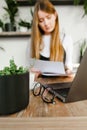 Background. A flowerpot, glasses and a laptop on a background of a girl sitting in a cafe and studying with papers in her hands.