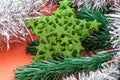 Background in the form of Christmas tree decorations - green branch of artificial spruce, green sparkling star and silver rain on Royalty Free Stock Photo