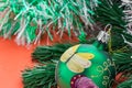 Background in the form of Christmas tree decorations - a large painted green ball, a green branch of artificial spruce and silver Royalty Free Stock Photo