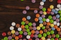 Background in the form of small round colored candies sprinkled on a wooden background Royalty Free Stock Photo