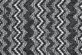 Background in the form of a woolen product with a pattern of alternating vertical black and white zigzags