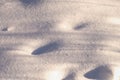 Background with a fragment of an uneven snow surface with pits and shadows