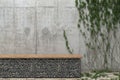 Background with a gray concrete wall with ivy and a bench of stones. Front view with copy space. 3D rendering.