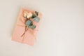 Background for greetings. Gift wrapping in soft pink paper with dry eucalyptus branch on a light concrete background Royalty Free Stock Photo