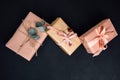 Background for greetings. Gifts wrapping in soft pink paper with dry eucalyptus branch on a black concrete background Royalty Free Stock Photo