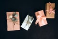 Background for greetings. Gifts wrapping in soft pink paper with dry eucalyptus branch on a black concrete background Royalty Free Stock Photo