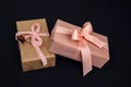 Background for greetings. Gifts wrapping in soft pink paper with dry flower on a black concrete background Royalty Free Stock Photo