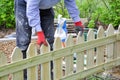 Background of hands of man installing a wooden fence in the garden and checking the level with a green