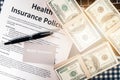 Background of health insurance gold card member with pen on health insurance policy document and US bank note on table