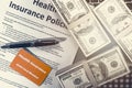 Background of health insurance gold card member with pen on health insurance policy document and US bank note on table