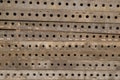 Horizontally laid black iron plates perforated with round holes with scratches and cement traces, for organization of formwork