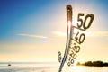 Ocean with people, bright sun and a big thermometer