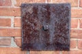 Brick wall of home exterior with large metal plate attached rusted with age Royalty Free Stock Photo