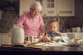 Background image cookbook, table, rolling pin, focus on the foreground. Girl and her grandmother cooking on kitchen. Royalty Free Stock Photo