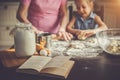 Background image cookbook, table, rolling pin, focus on the foreground. Girl and her grandmother cooking on kitchen.