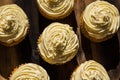A background image of five delicious cream colored cupcakes on a wooden board