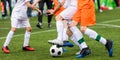 Background image of football game. Legs of soccer players kicking a black and white soccer ball on artificial grass pitch