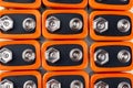 Background image of a large number of orange batteries, standing in several rows