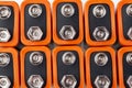 Background image of a large number of orange batteries, standing in several rows