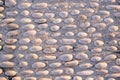 Background image of old cobblestone road backlit with low sunlight. Stone texture close up. Small pebbles on the road Royalty Free Stock Photo