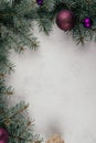 Background image of white surface with branches of Christmas tree, decorations and purple balls. Vertical. Copy space Royalty Free Stock Photo