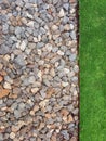 Background of irregular stones and grass. Pebble wall. Texture of irregular small stones and green background. Gardens and parks Royalty Free Stock Photo