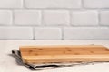 Background kitchen with cutting board on white wooden table, with linen tablecloth against the background a brick wall Royalty Free Stock Photo