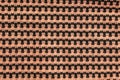 The background of a knitted fabric is orange-black with a regular geometric pattern. Openwork finely knitted woolen fabric