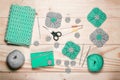 Background with knitting tools and accessories. Green crocheted square napkins, balls of wool yarn, scissors, hooks on light