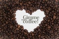 Background made of coffee beans in a heart shape with message `Gimme more coffee!`