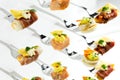 Background of mixed canapes on metal forks. White background