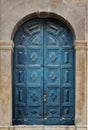 Background with an old, historic and weathered blue wooden door, in a stone wall with a round arch in Sicily, Italy