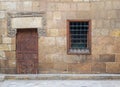 Background of old stone bricks wall with grunge wooden closed door and window with iron grid Royalty Free Stock Photo