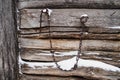 Background of old wooden logs with snow and hanging rusty chain.