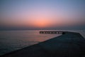 Background with old wooden pier in the sea at sunset. The sun goes down in the water Royalty Free Stock Photo